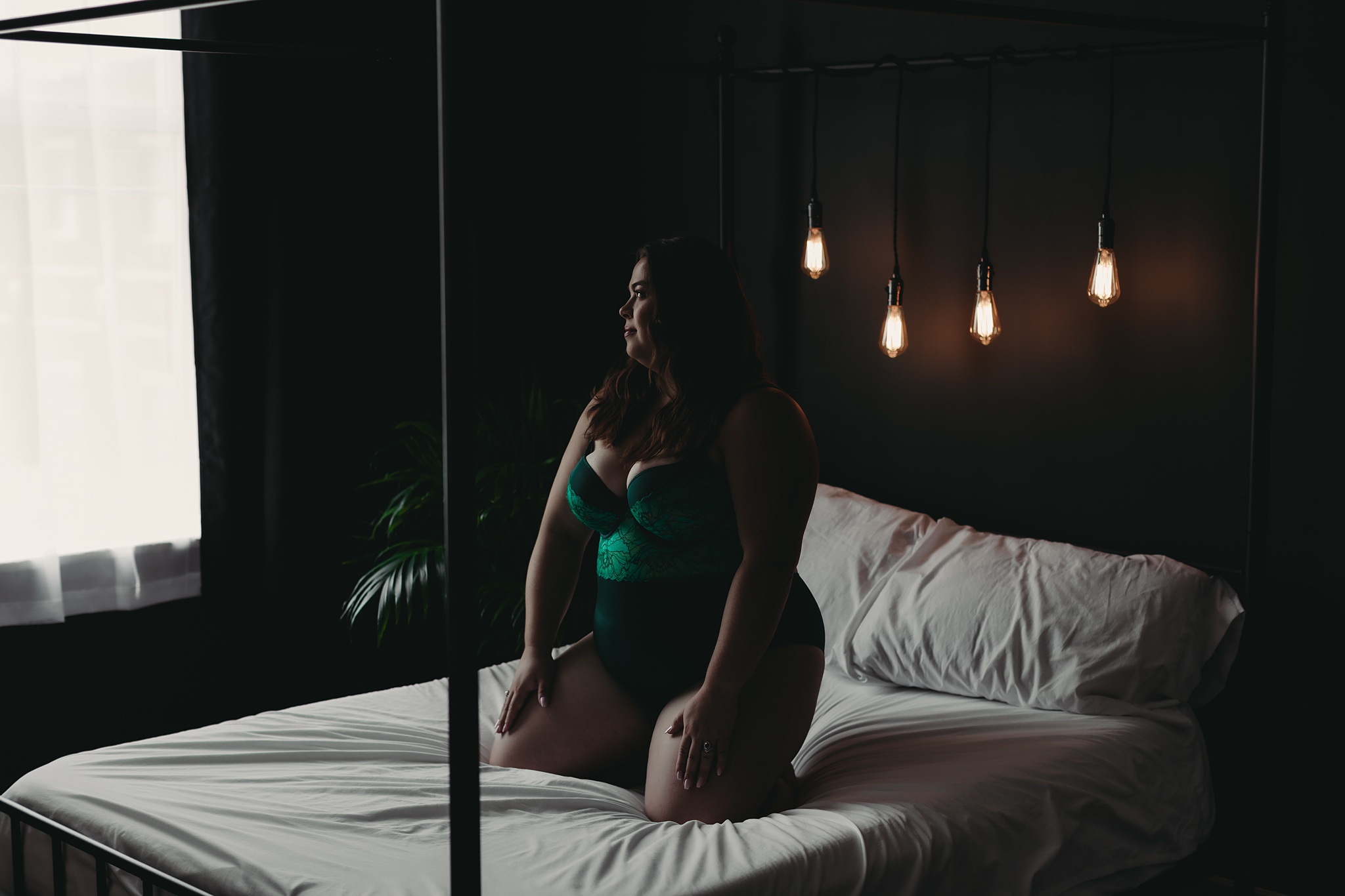 woman sitting in bed wearing green lingerie for Grand Haven MI boudoir shoot
