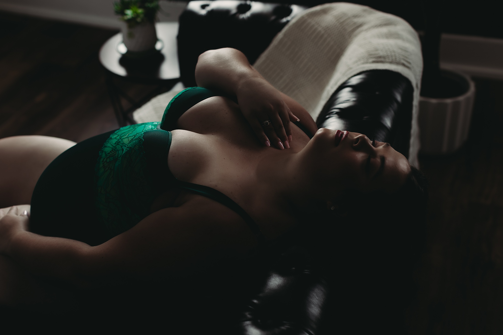 woman laying on black leather couch for boudoir shoot in Grand Haven MI boudoir studio