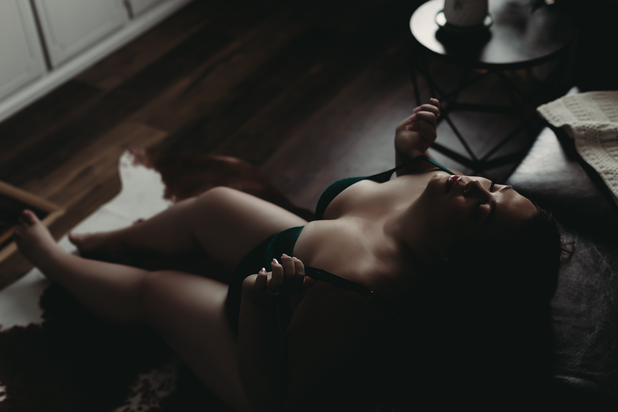 woman sitting on the floor holding bra straps for Grand Haven MI boudoir shoot