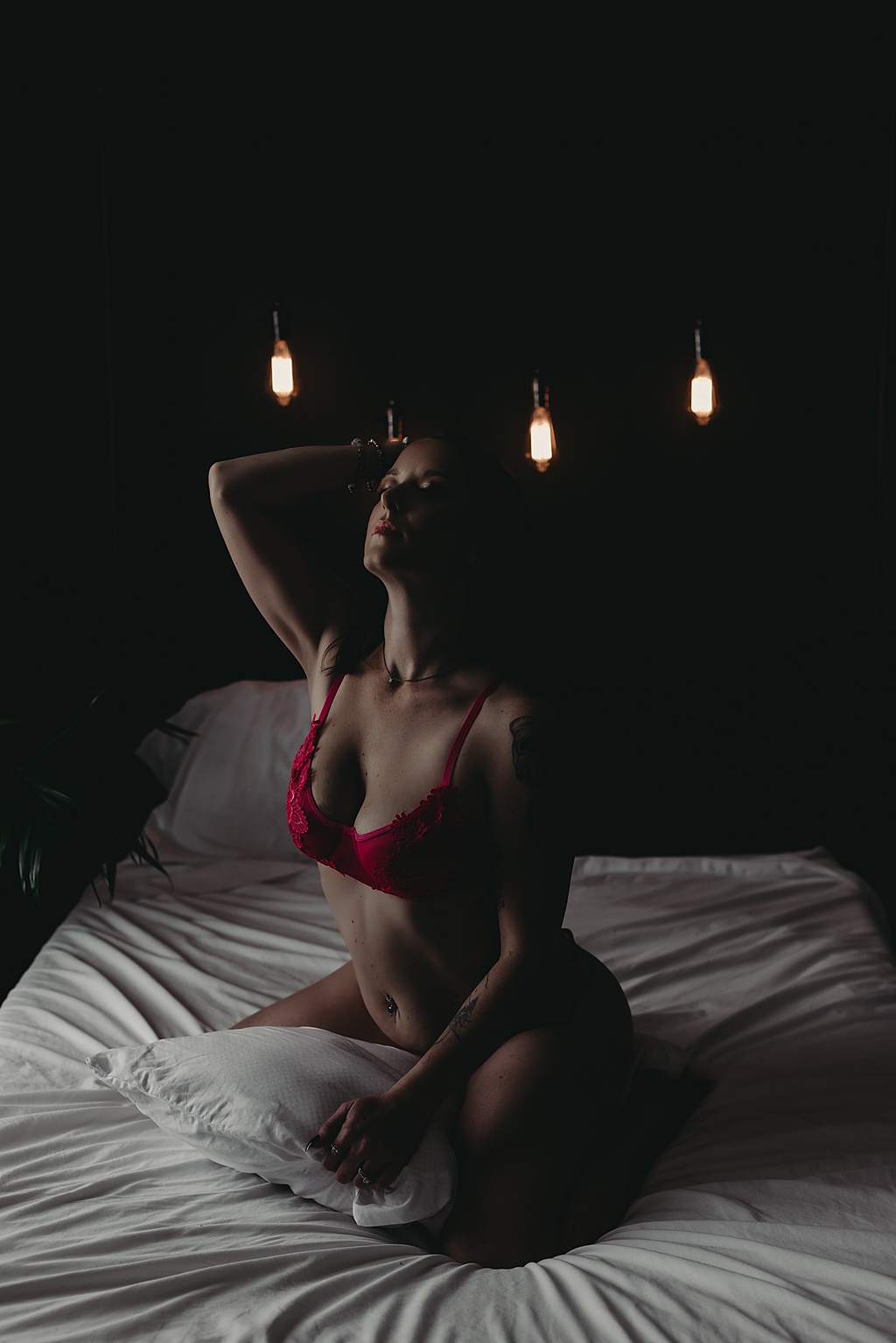 woman sitting in bed wearing pink lingerie for boudoir photoshoot