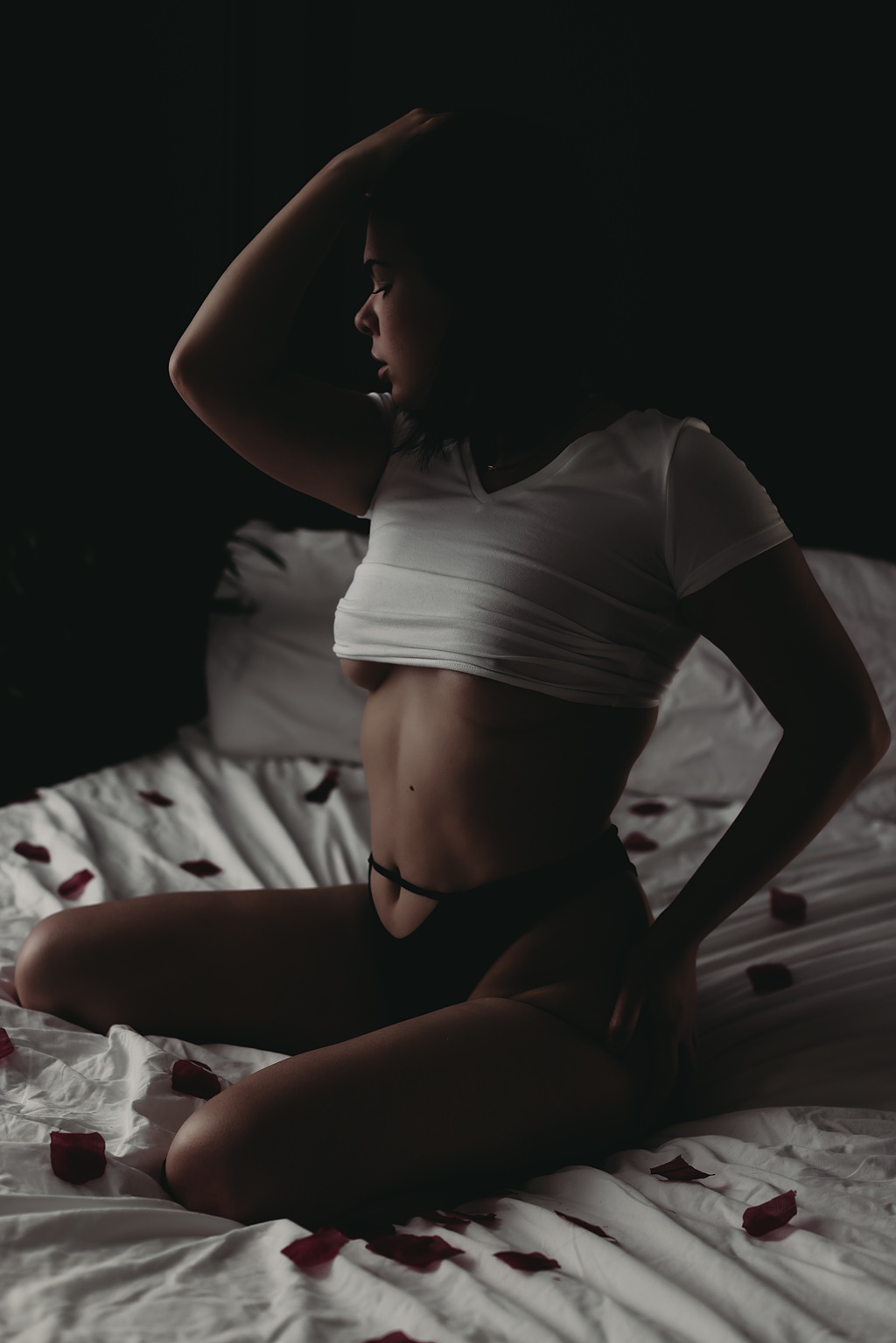 woman sitting in bed wearing crop top and black panties for Grand Haven MI boudoir photoshoot