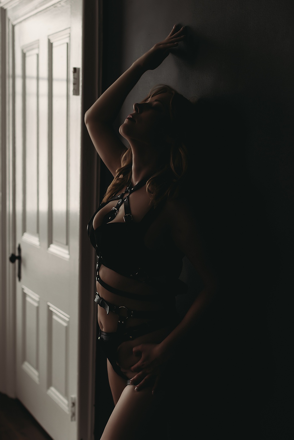 woman leaning against the wall wearing black lingerie