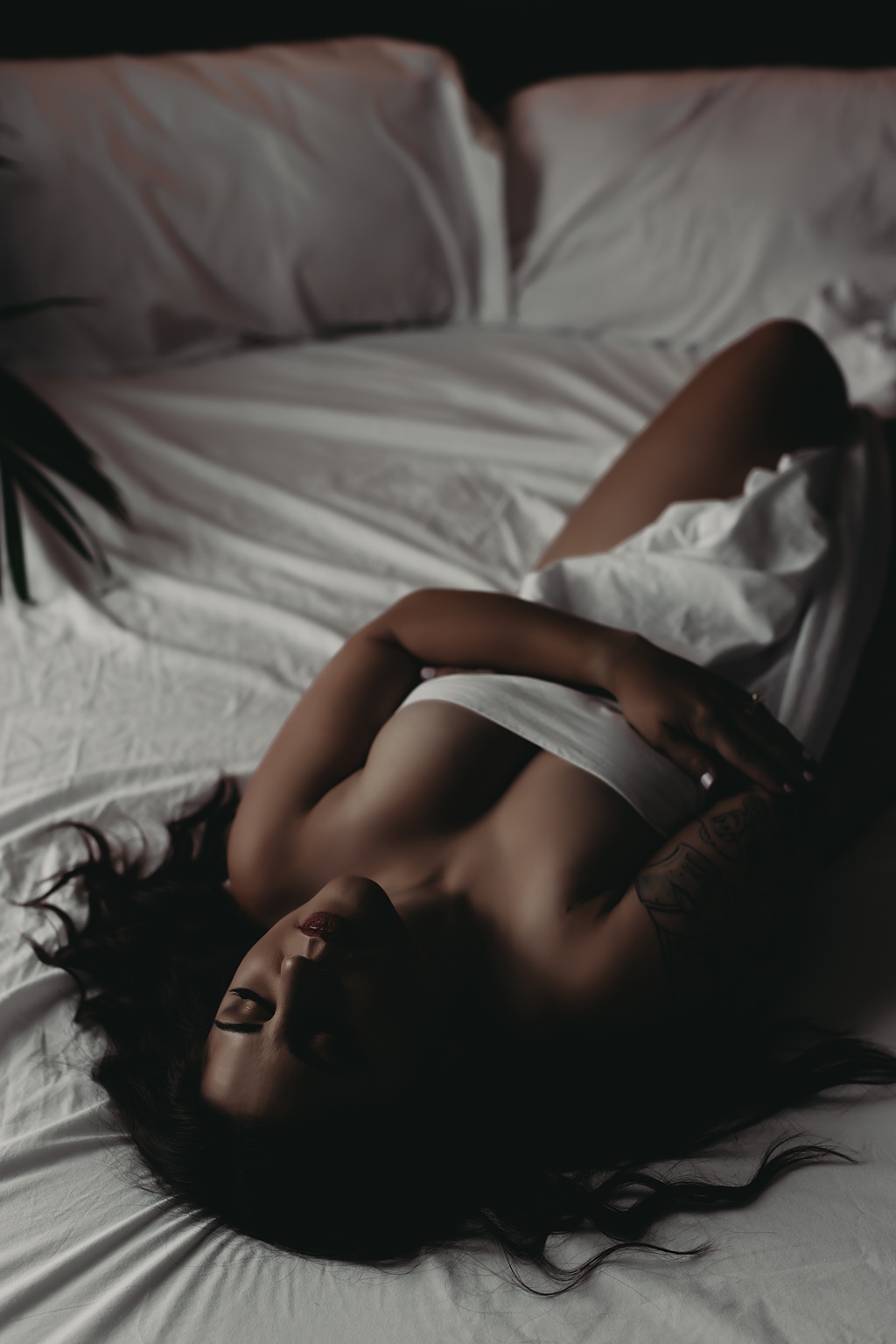 woman laying on her back in bed wrapped by a white sheet